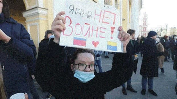 Eine Frau hält ein Plakat hoch mit der Aufschrift: Нет войне / Nein zum Krieg