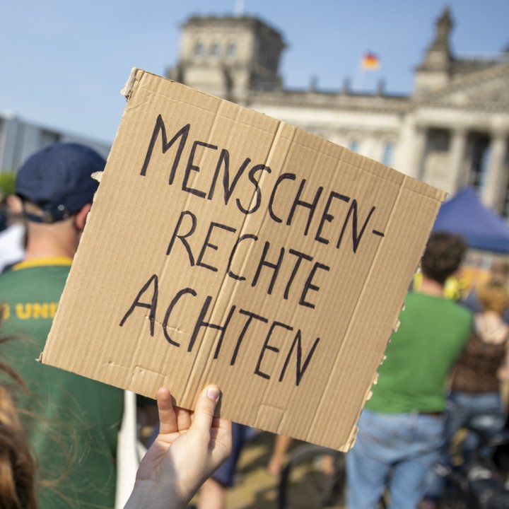 Eine Demonstrantin mit dem Rücken zum Fotografen. Auf dem Demonstrationsschild steht: Menschenrechte achten!