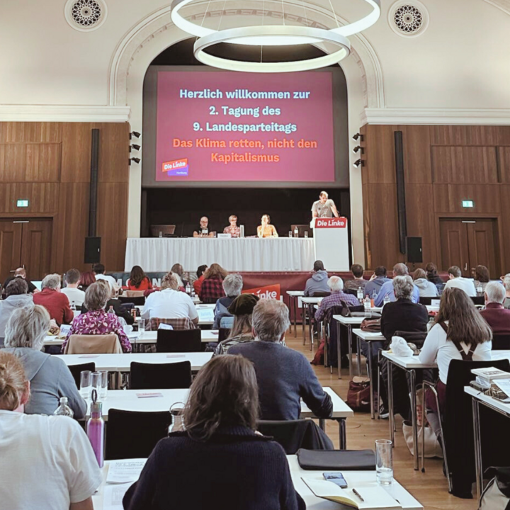 Foto vom Parteitag, Delegierte sitzen an ihren Tischen. Das Präsidium sitzt im Hintergrund. Thomas Ivan spricht zum Publikum.